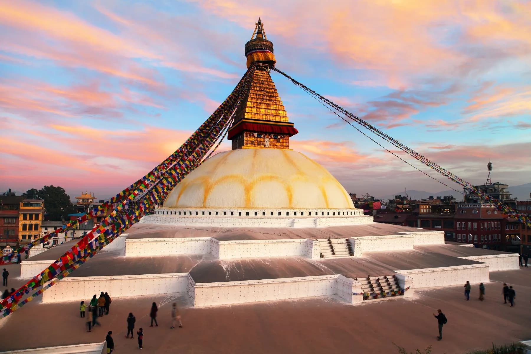 Boudhanath Stupa at sunset, prayer flags streaming from its spire