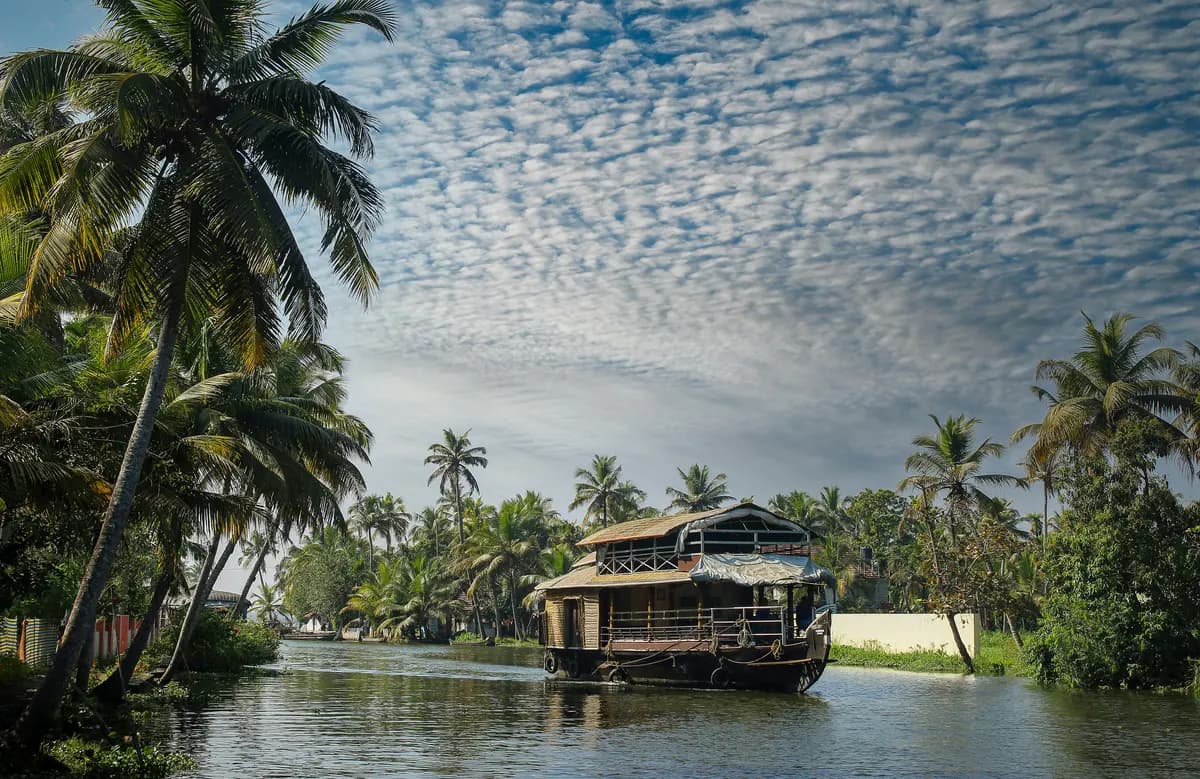 A traditional houseboat on a palm-lined waterway near Thekkady, Kerala