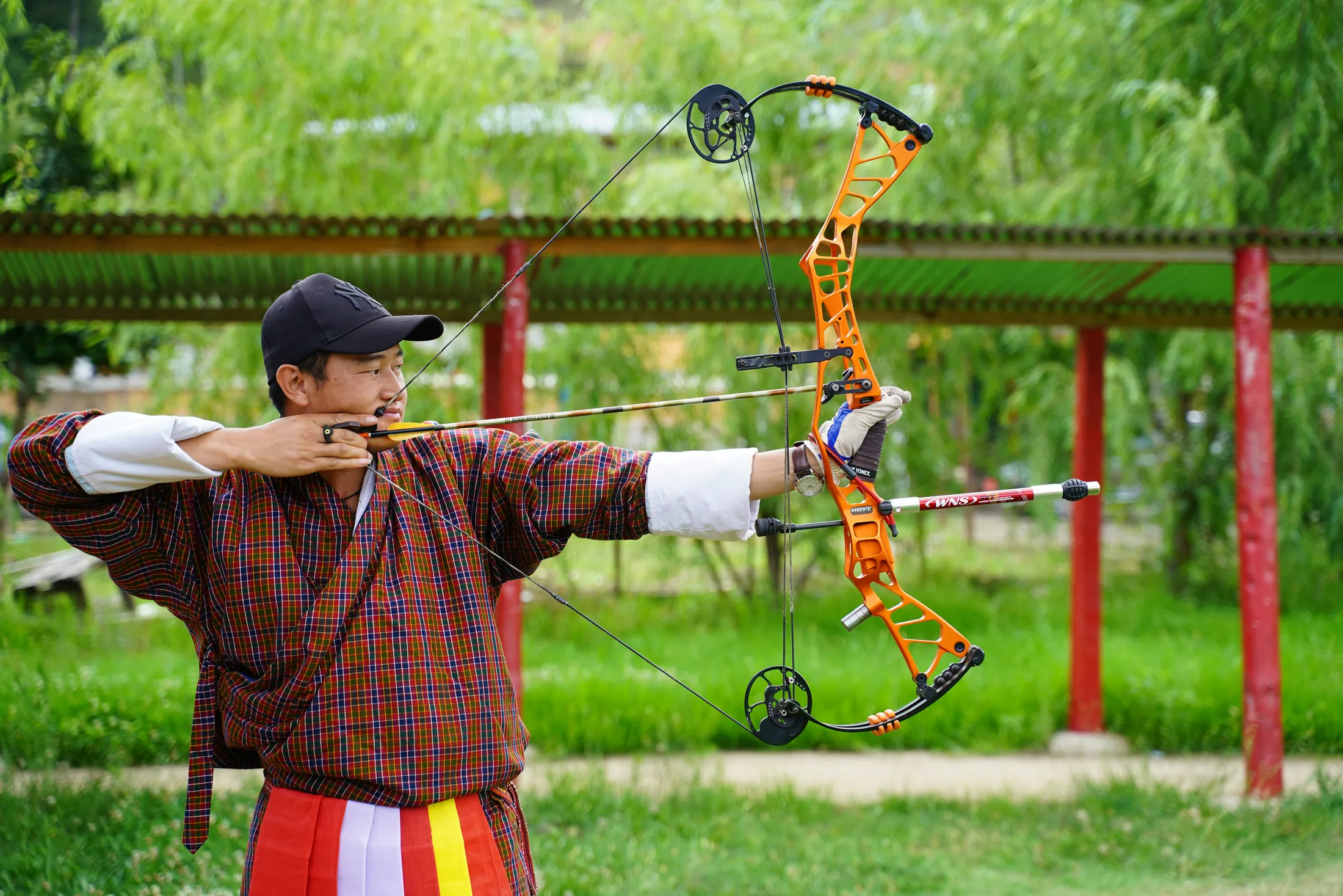 A Bhutanese archer in traditional dress taking aim